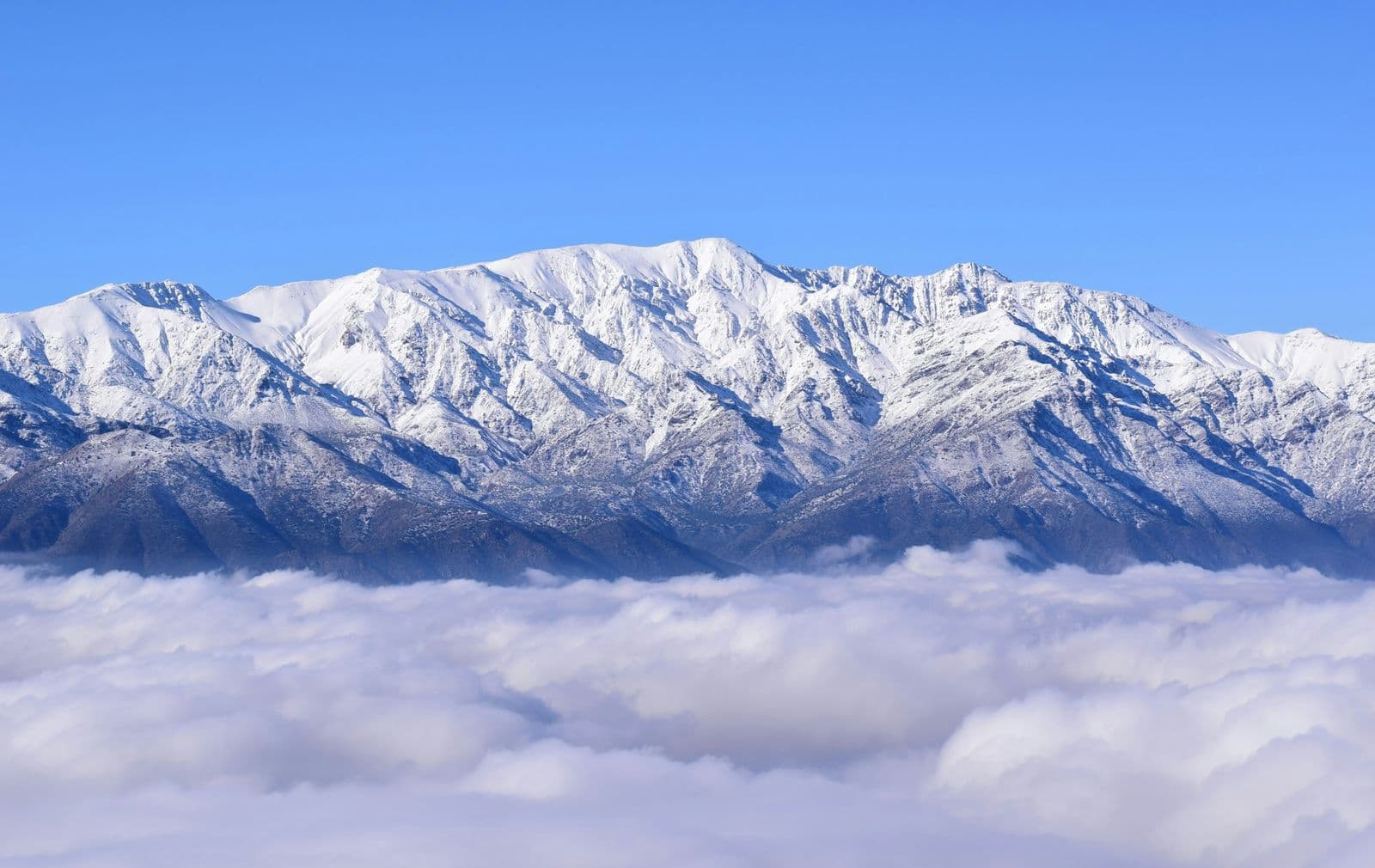 Picos nevados da Cordilheira dos Andes acima de um mar de nuvens.