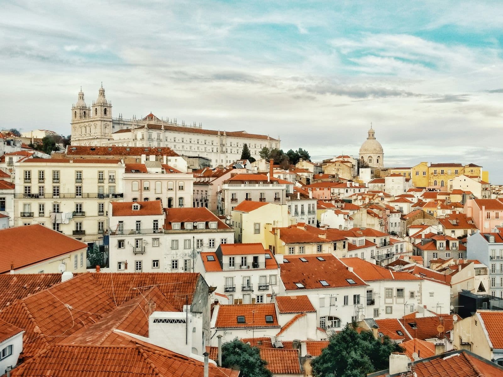 Telhados alaranjados da Alfama, em Lisboa, com o rio Tejo ao fundo.